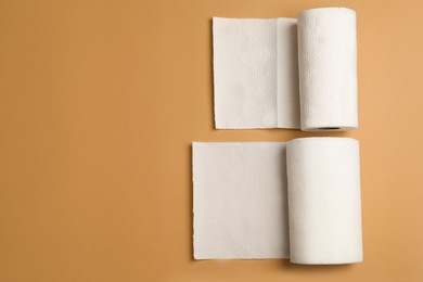 Photo of Rolls of white paper towels on brown background, flat lay. Space for text