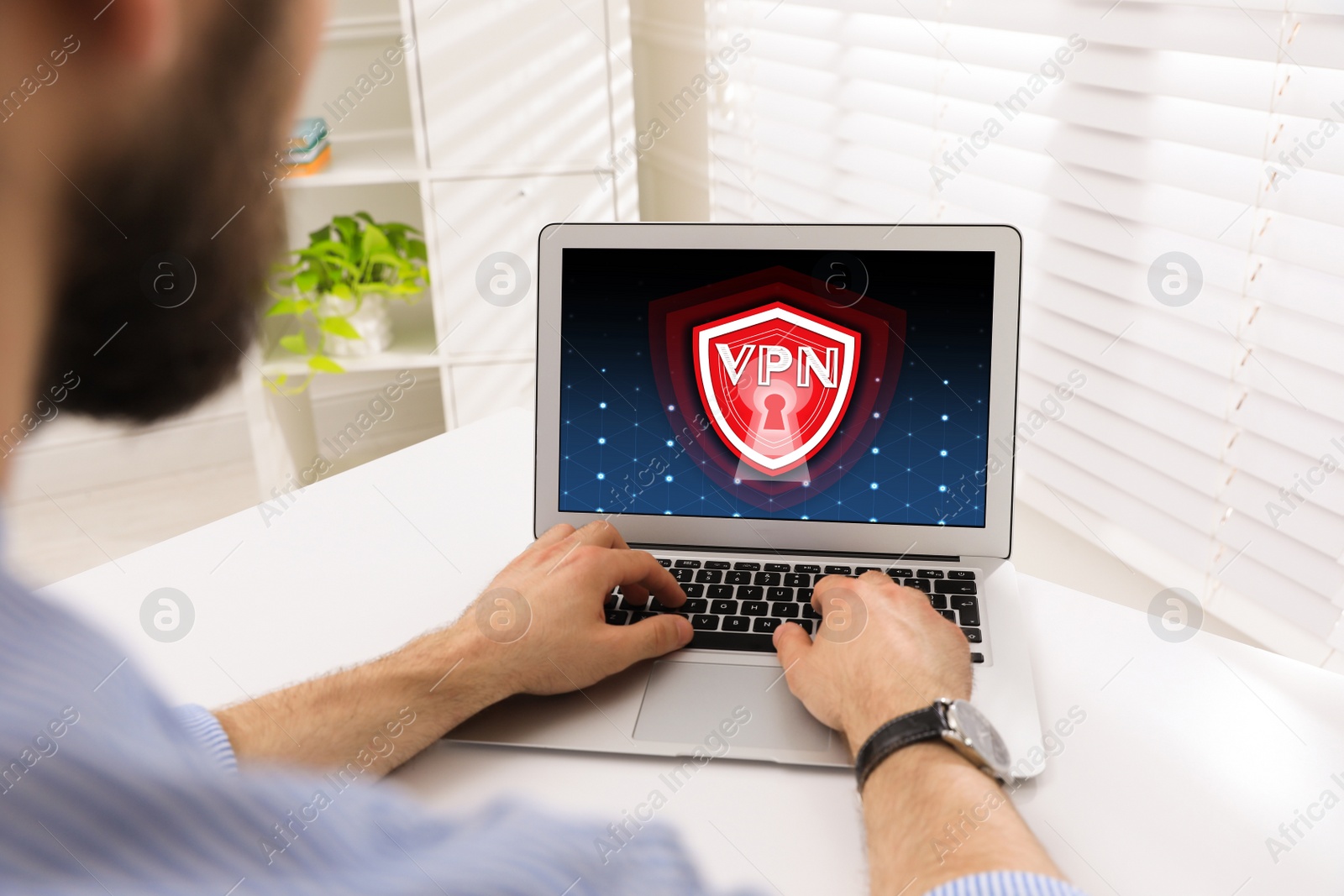 Image of Man using laptop with switched on VPN at white table, closeup