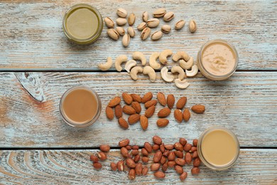Photo of Different types of delicious nut butters and ingredients on light blue wooden table, flat lay