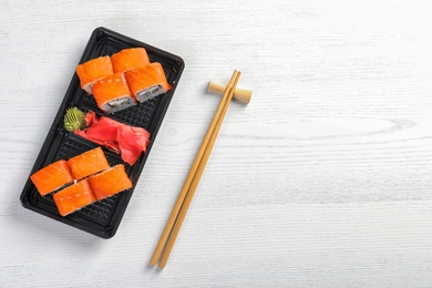Tasty sushi rolls served on white wooden table, top view with space for text. Food delivery
