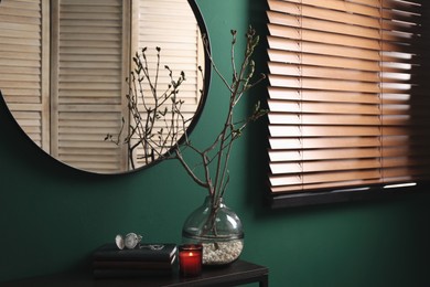 Photo of Beautiful tree twigs in vase on table near green wall