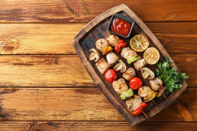 Photo of Delicious shish kebabs with grilled vegetables served on wooden table, top view. Space for text