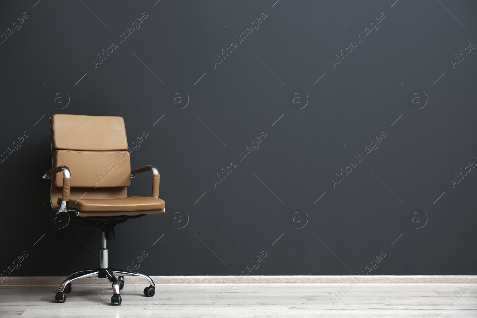 Photo of Comfortable office chair near black wall indoors. Space for text