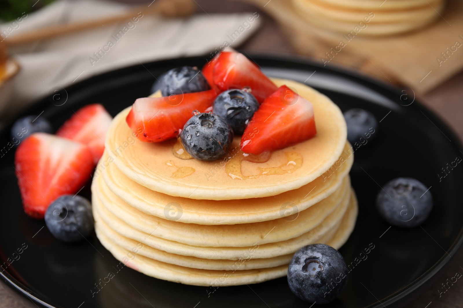 Photo of Delicious pancakes with strawberries and blueberries on table, closeup