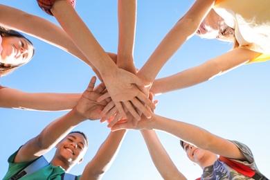 Photo of Group of children putting hands together outdoors. Summer camp