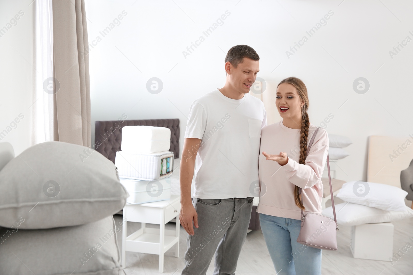 Photo of Happy couple choosing cushion in mattress store