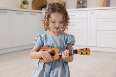 Little girl playing toy guitar in kitchen