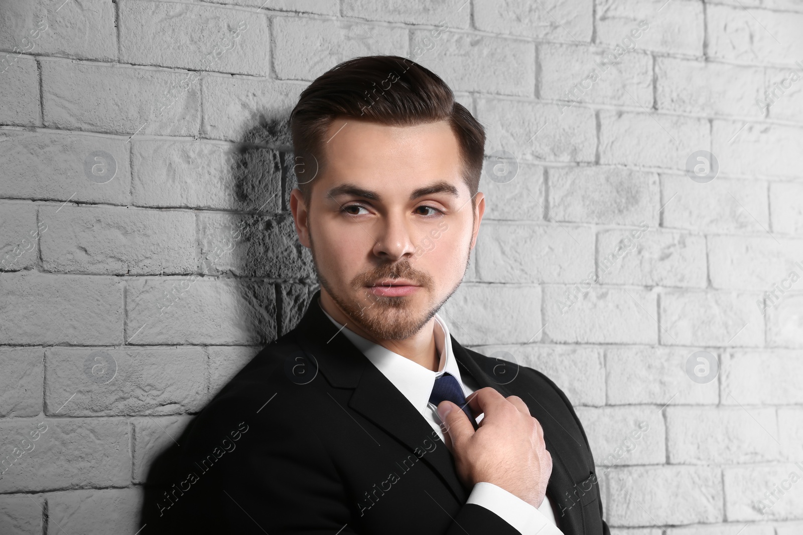 Photo of Portrait of young man with beautiful hair on brick wall background