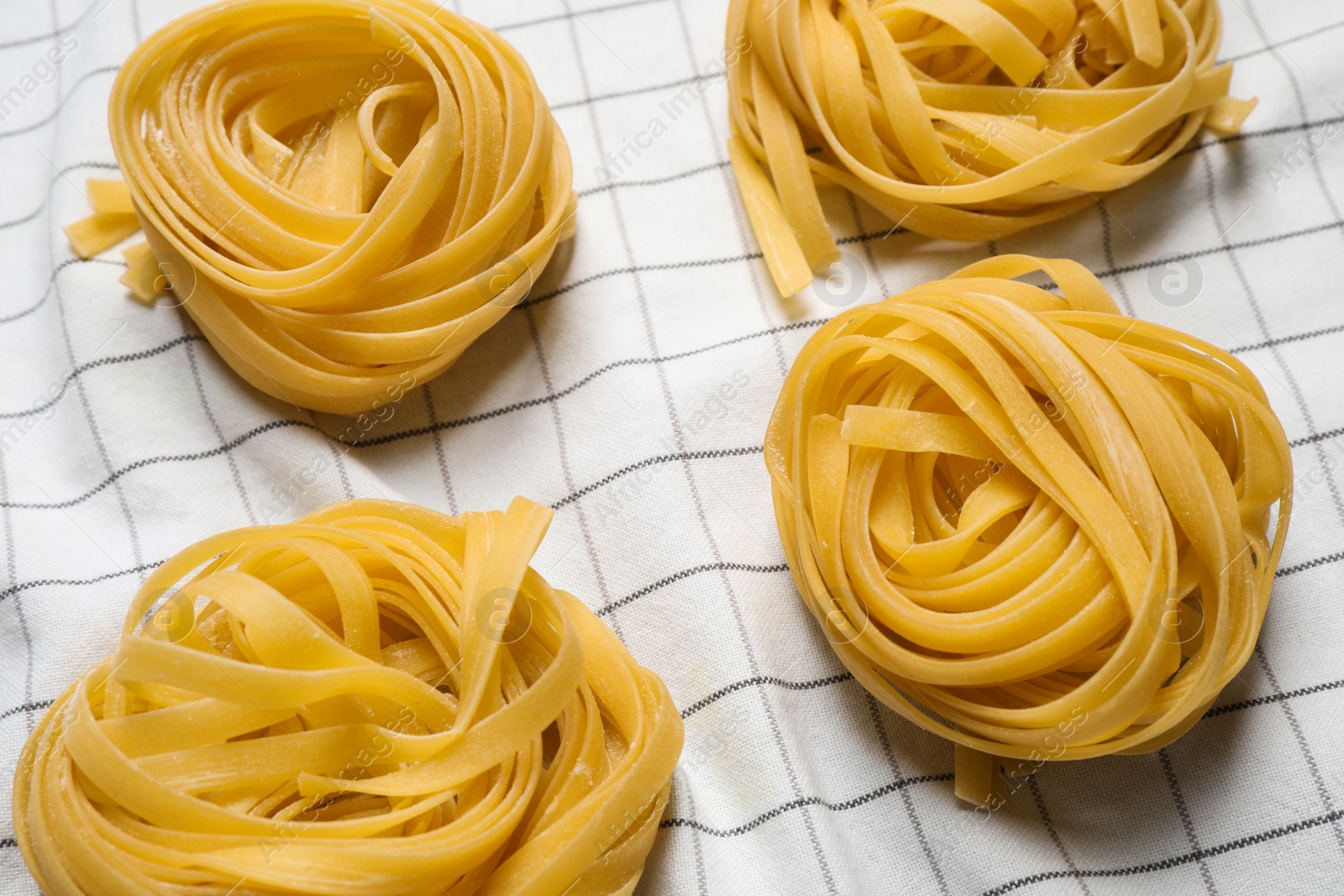 Photo of Tagliatelle pasta on white tablecloth, flat lay