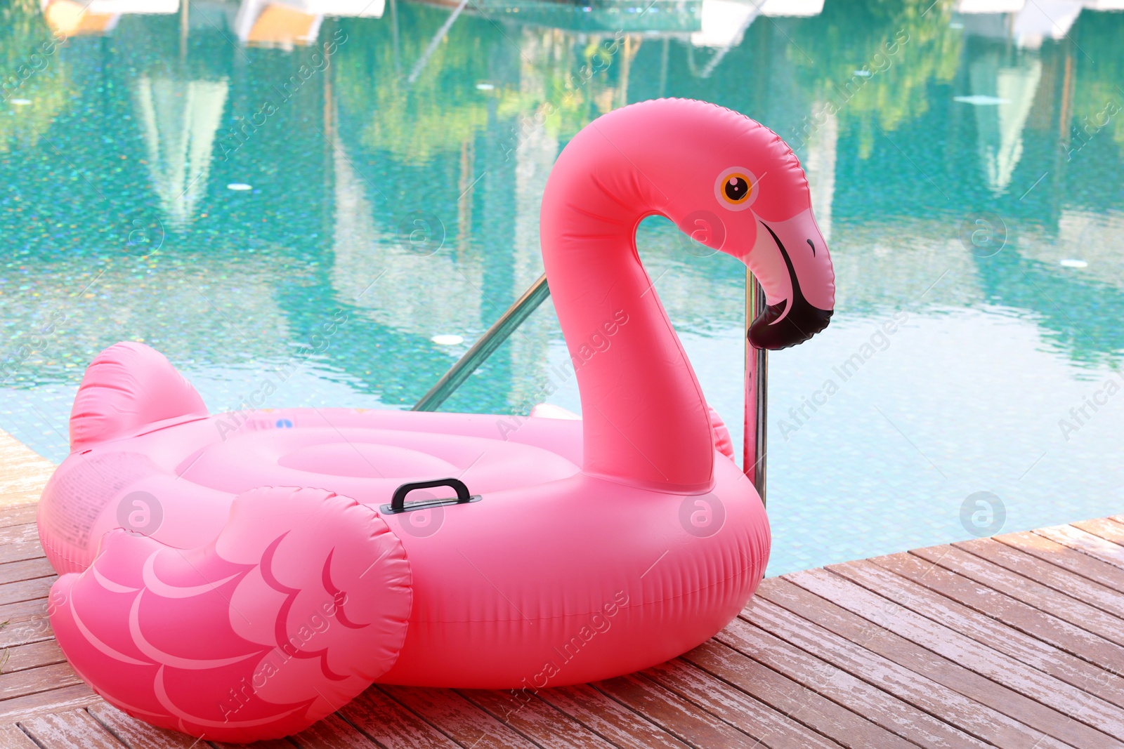 Photo of Float in shape of flamingo on wooden deck near swimming pool at luxury resort