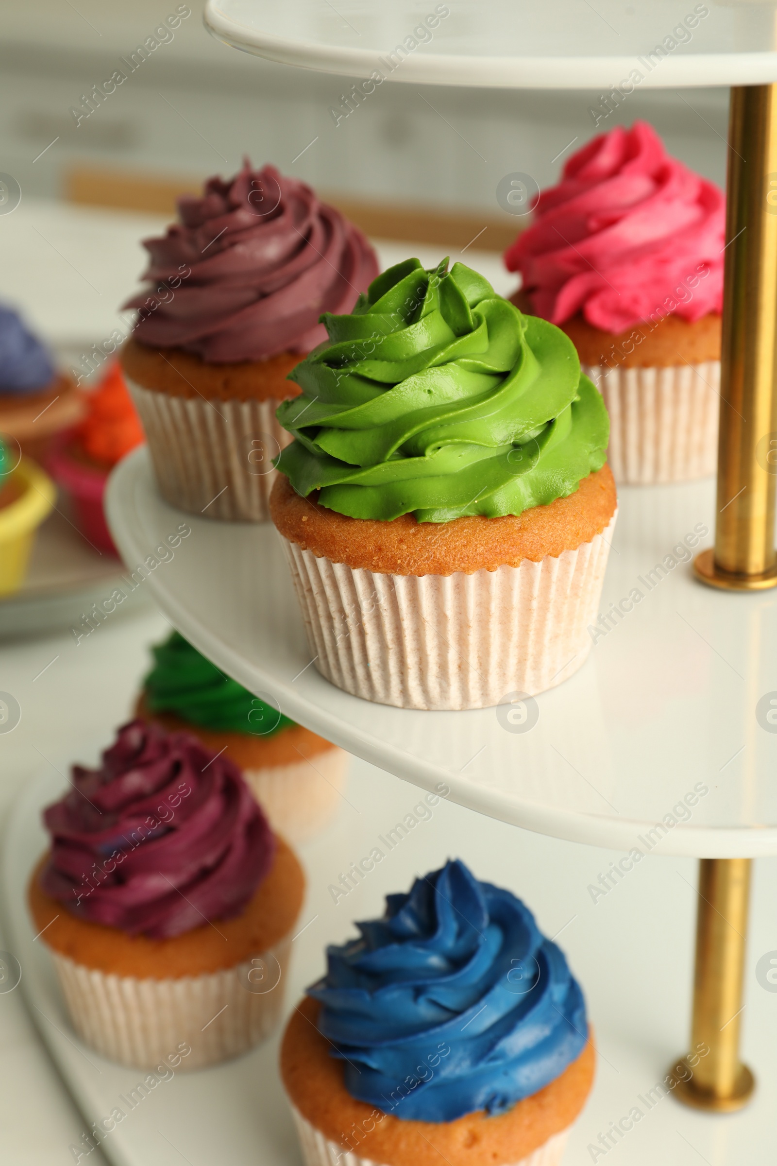 Photo of Delicious cupcakes with colorful cream on stand, closeup