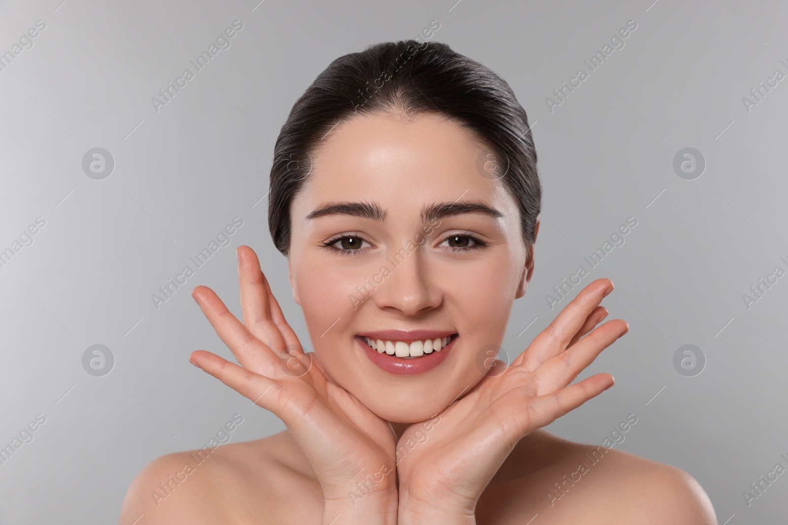 Photo of Young woman massaging her face on grey background