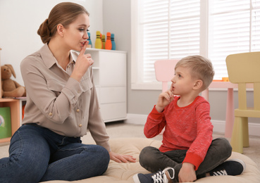 Speech therapist working with little boy in office