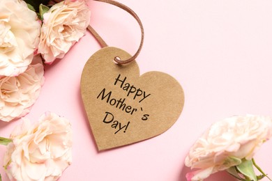 Happy Mother's Day. Heart shaped greeting label and beautiful flowers on pink background