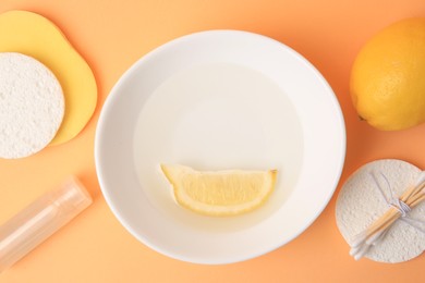 Photo of Lemon face cleanser. Fresh citrus fruits and personal care products on pale orange background, flat lay