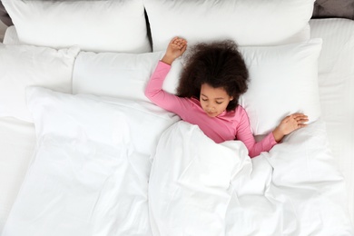 Photo of Cute little African-American girl sleeping in bed, top view