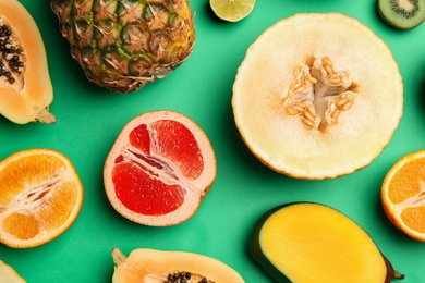 Photo of Flat lay composition with tasty melon and fresh tropical fruits on green background