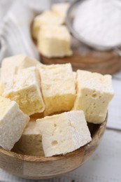 Photo of Bowl with tasty marshmallows on white wooden table, closeup