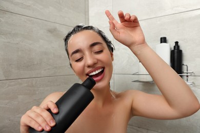 Photo of Washing hair. Happy woman with bottle singing in shower