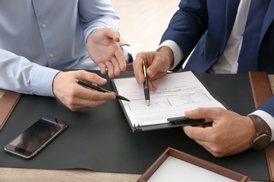 Photo of Lawyer working with client at table in office, focus on hands