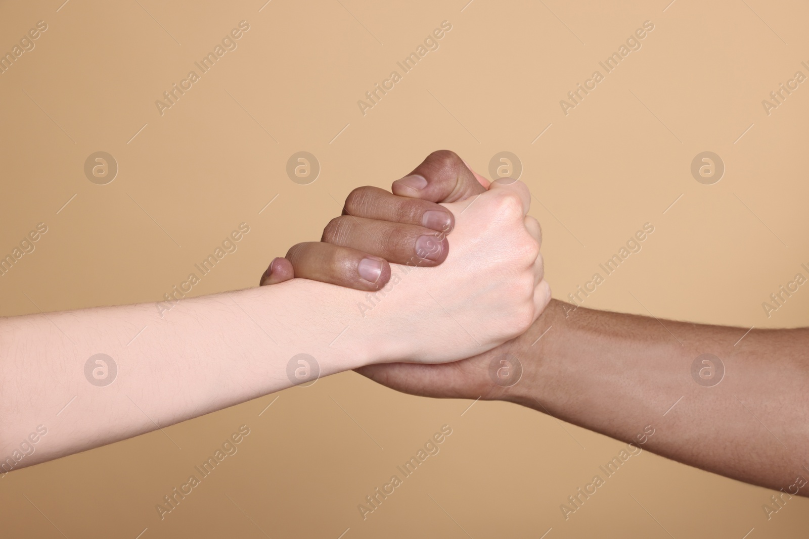 Photo of International relationships. People clasping hands on light brown background, closeup