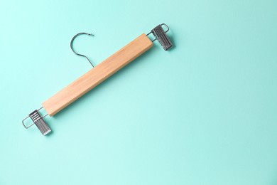 Wooden hanger with clips on light blue background, top view. Space for text