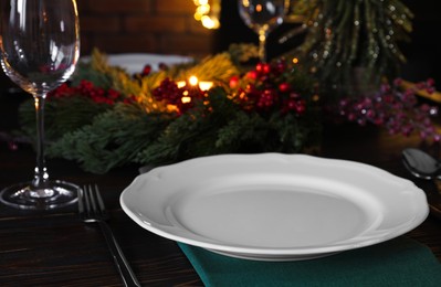 Photo of Plate, cutlery, glass and festive decor on wooden table