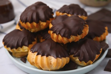 Delicious profiteroles with chocolate spread on table, closeup
