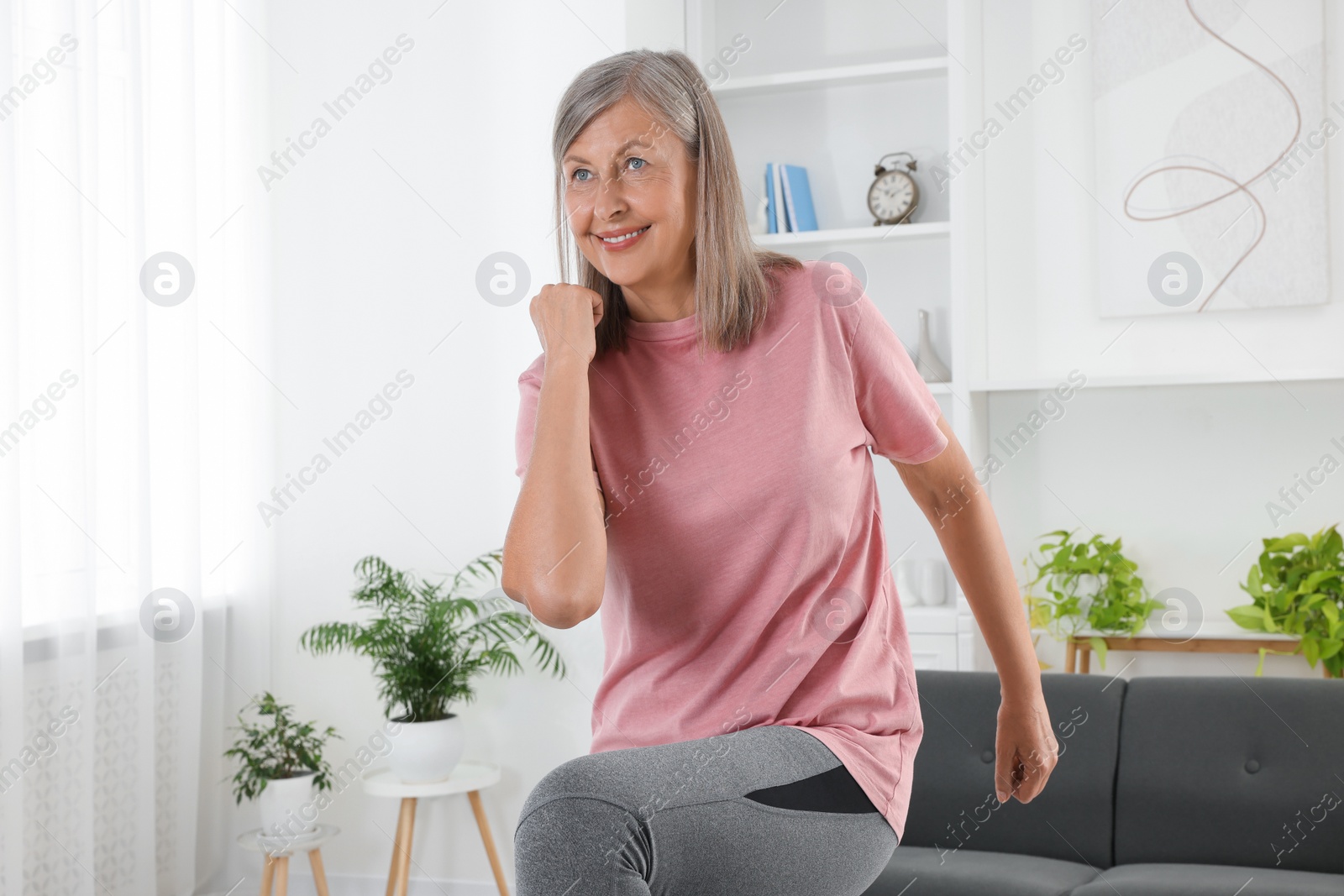 Photo of Senior woman in sportswear doing exercises at home