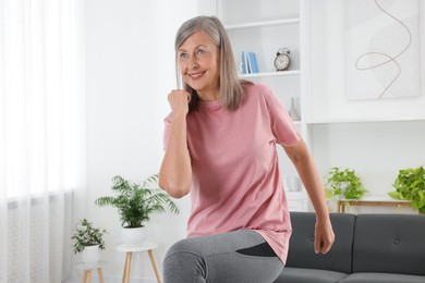 Photo of Senior woman in sportswear doing exercises at home