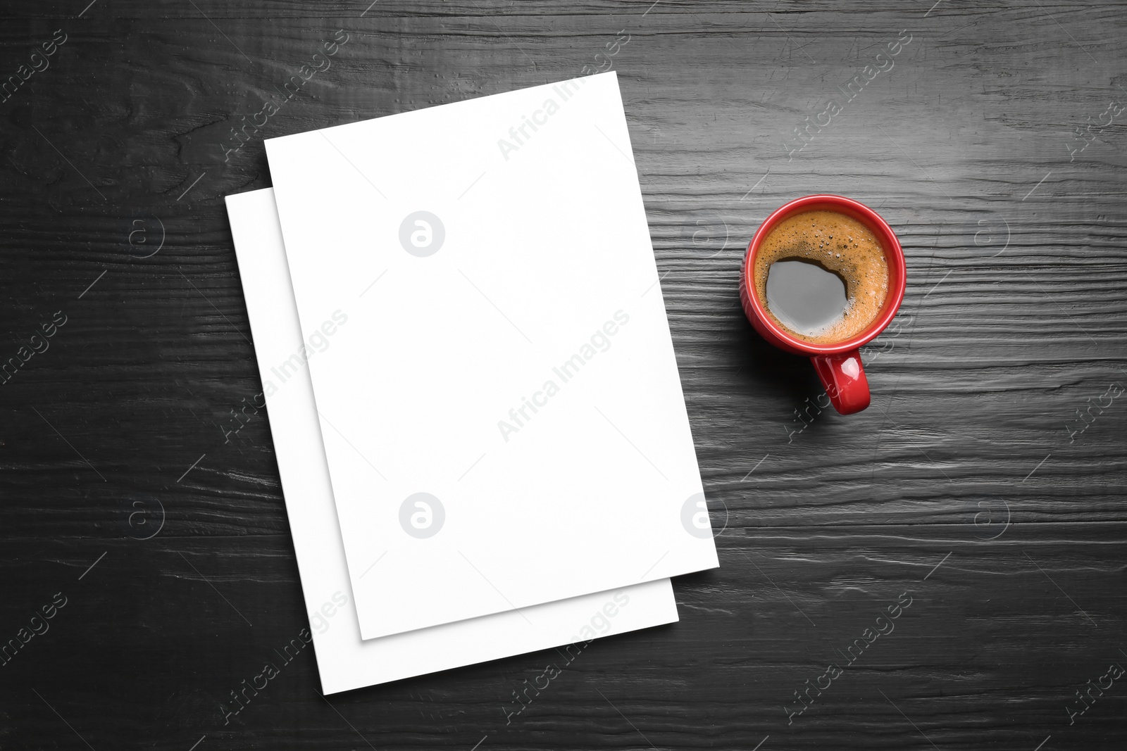 Photo of Blank paper sheets for brochure and cup of coffee on black wooden background, flat lay. Mock up