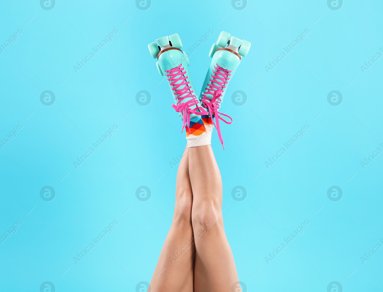 Photo of Young woman with retro roller skates on color background, closeup