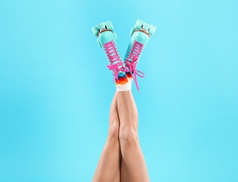 Photo of Young woman with retro roller skates on color background, closeup