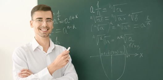 Image of Happy teacher near chalkboard in classroom. Banner design