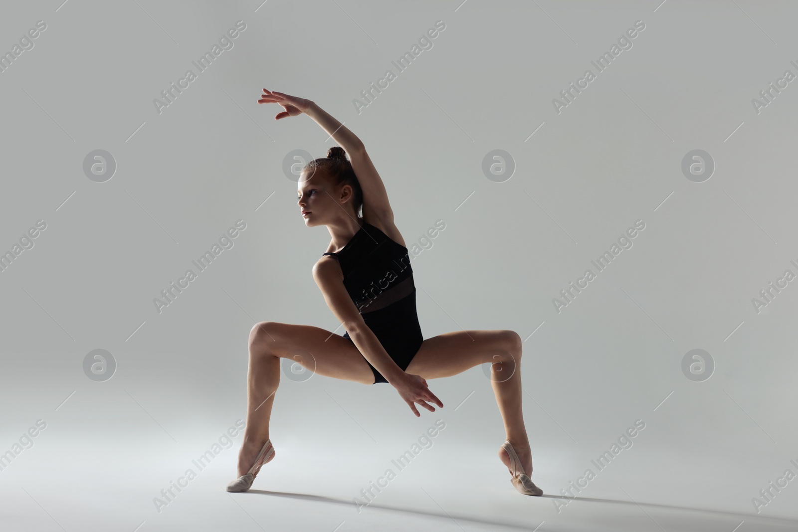 Photo of Cute little girl doing gymnastic exercise on white background