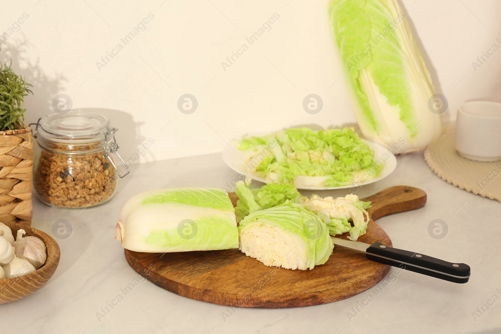 Photo of Cut fresh chinese cabbage and knife on white kitchen table