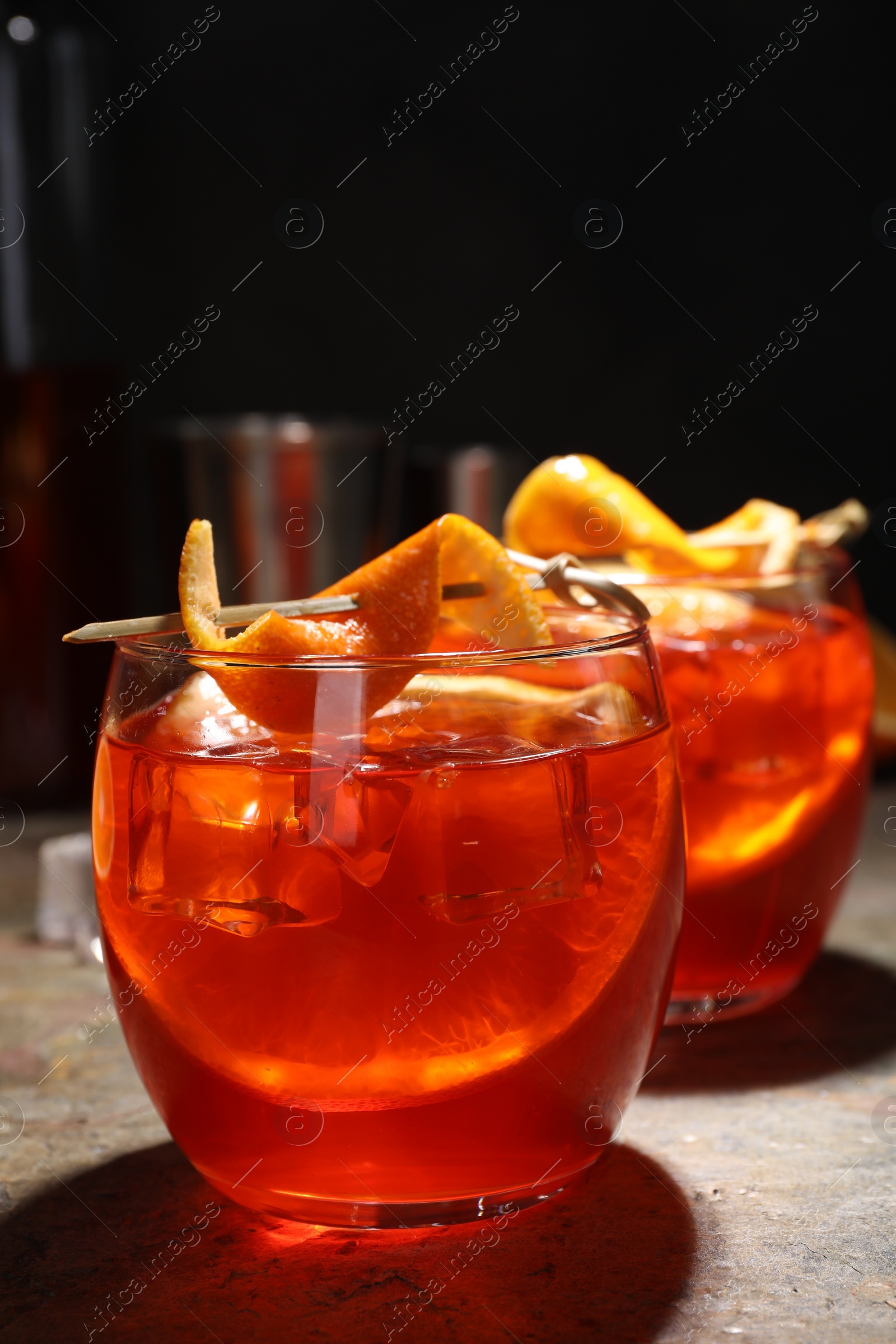 Photo of Aperol spritz cocktail, ice cubes and orange slices in glasses on grey textured table, closeup