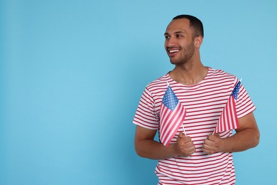 Photo of 4th of July - Independence Day of USA. Happy man with American flags on light blue background, space for text