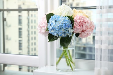 Beautiful hydrangea flowers in vase on windowsill indoors