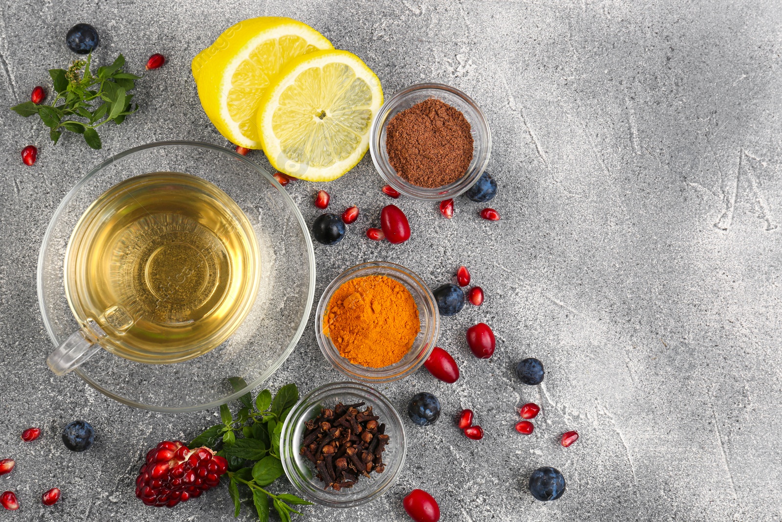 Photo of Cup with delicious immunity boosting tea and ingredients on grey table, flat lay. Space for text