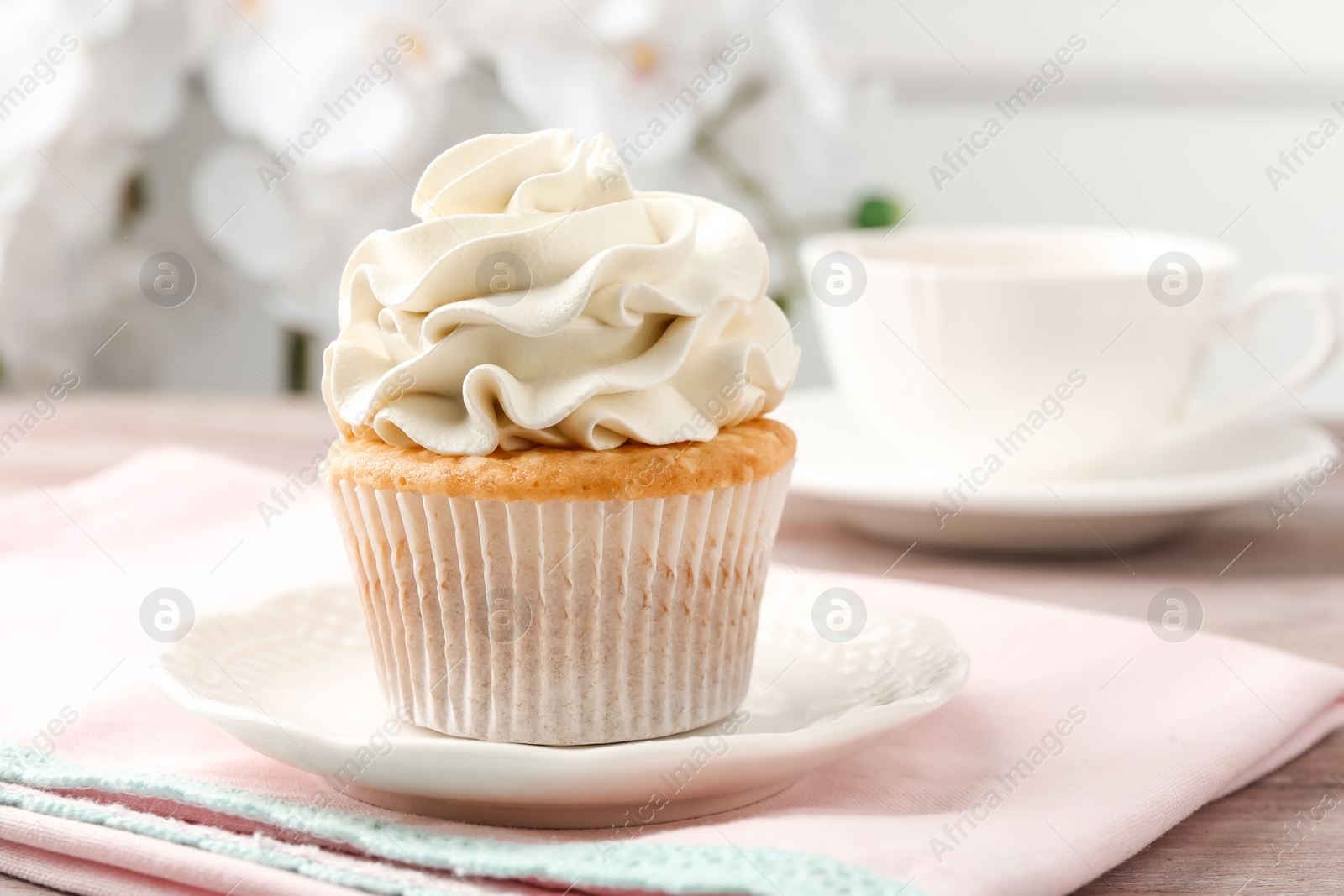 Photo of Tasty cupcake with vanilla cream on pink wooden table, closeup