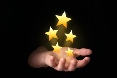 Man holding virtual stars on black background, closeup. Customer satisfaction score