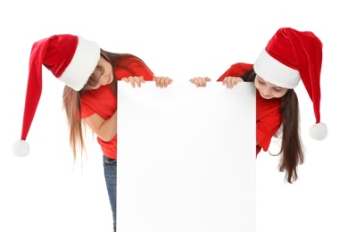 Photo of Cute little children in Santa hats with blank poster on white background. Christmas celebration
