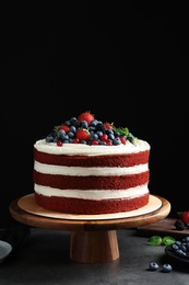 Stand with delicious homemade red velvet cake on table