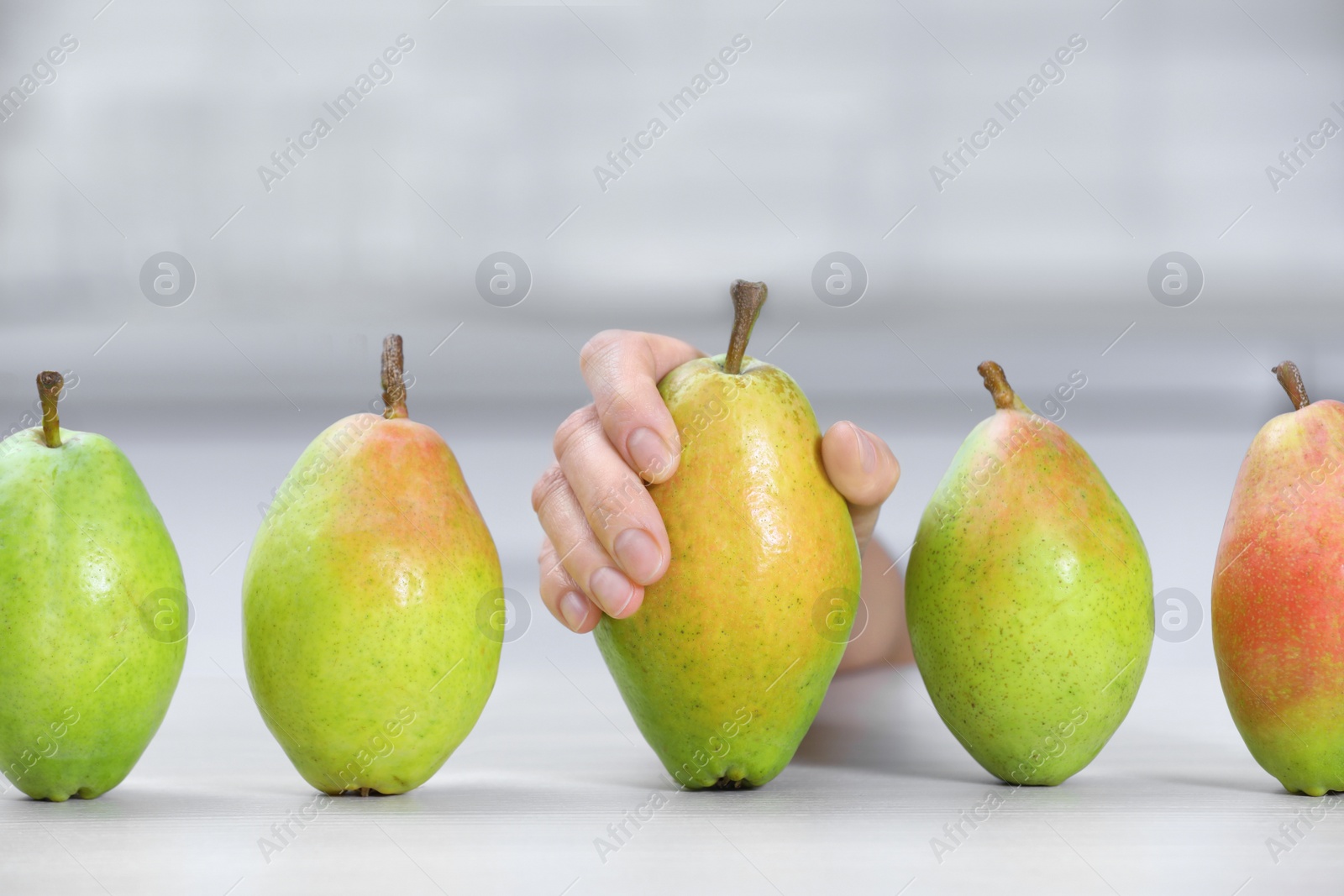 Photo of Woman taking fresh ripe pear from table in kitchen, closeup