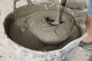 Photo of Worker mixing cement in bucket, closeup view
