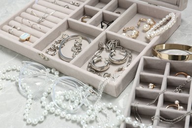 Photo of Jewelry boxes with many different accessories on light grey table, closeup