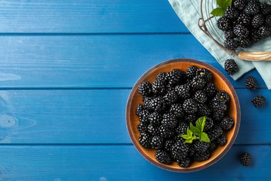 Fresh ripe blackberries on blue wooden table, flat lay. Space for text