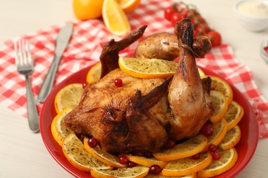 Photo of Baked chicken with orange slices on white wooden table, closeup