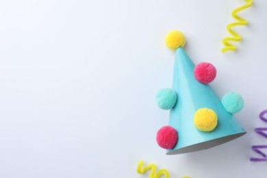 One blue party hat with pompoms on light background, top view. Space for text